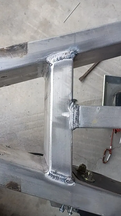 TIG-welded joints on an aluminum frame crossmember, beads at both ends and the side tube