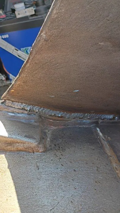 Fresh weld bead joining the side plate to the floor of a heavy equipment bucket