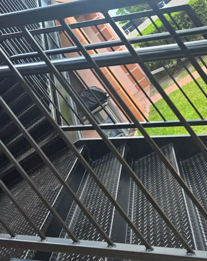 Diamond-plate steel stair treads behind a new steel railing
