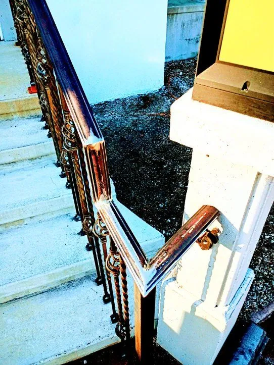 Ornamental scroll stair railing with a welded joint at the newel post beside a lamp pillar