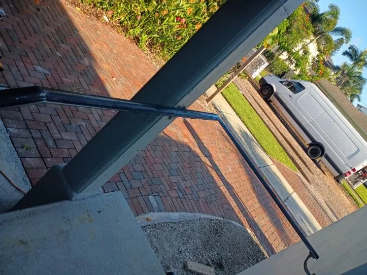 Black steel handrail at the front steps above a brick paver walkway