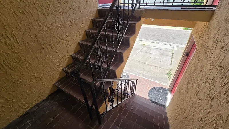 Steel stair railing running from the landing down a brick stairwell