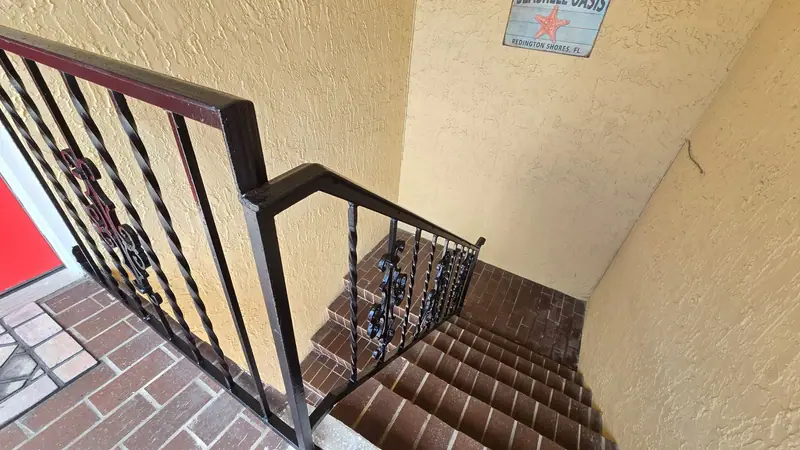 Twisted-bar steel stair railing with scroll panels in a condo stairwell