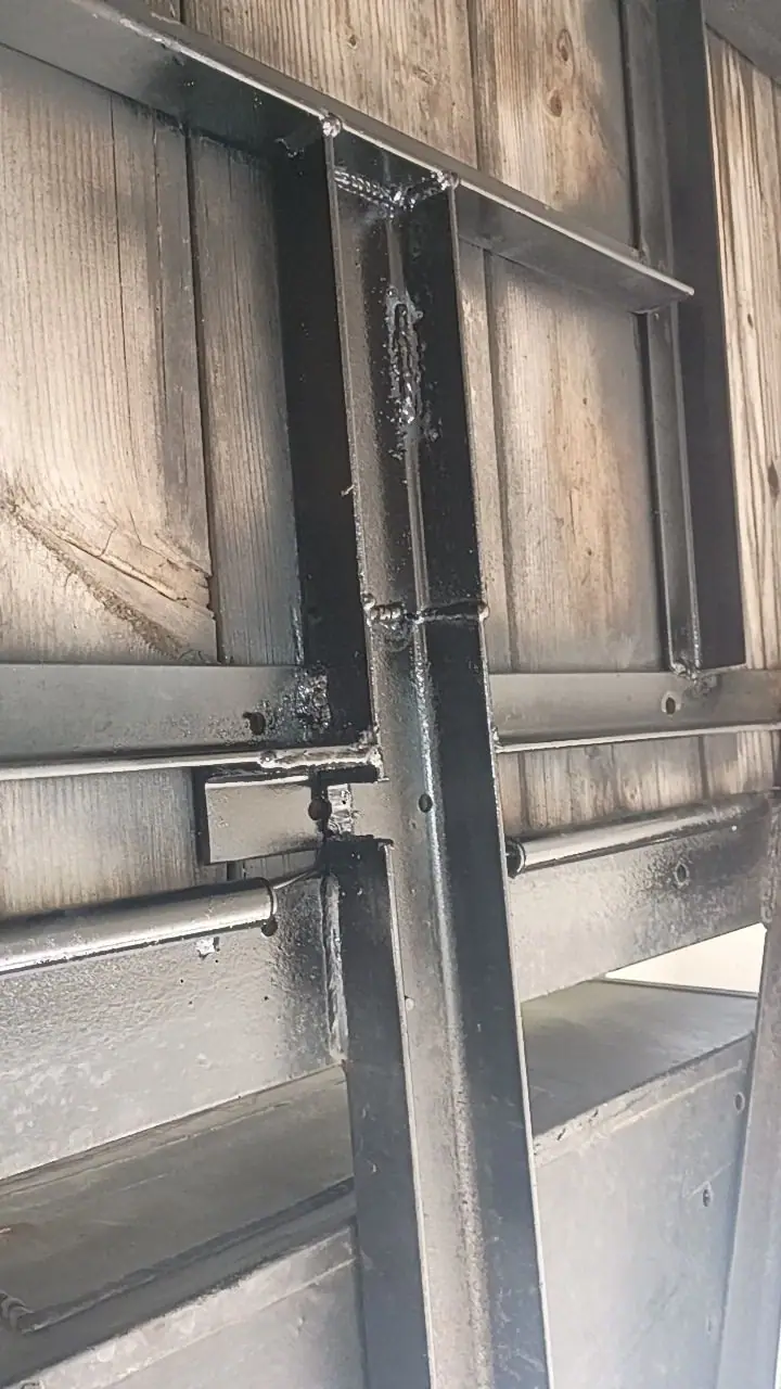 Welded steel framing against a wood-paneled wall