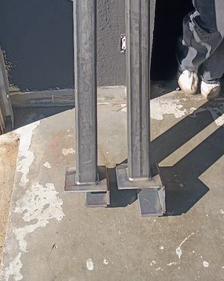 Two square steel posts with welded base plates standing in the shop
