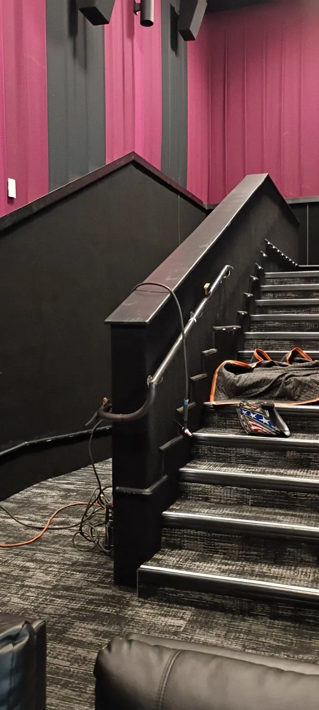 Long metal handrail installed along the black stairs of a movie theater
