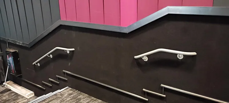 Metal stair handrails mounted along the dark wall of a movie theater auditorium