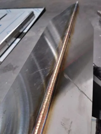 Close-up of a clean TIG weld bead along the edge of a sheet-metal panel