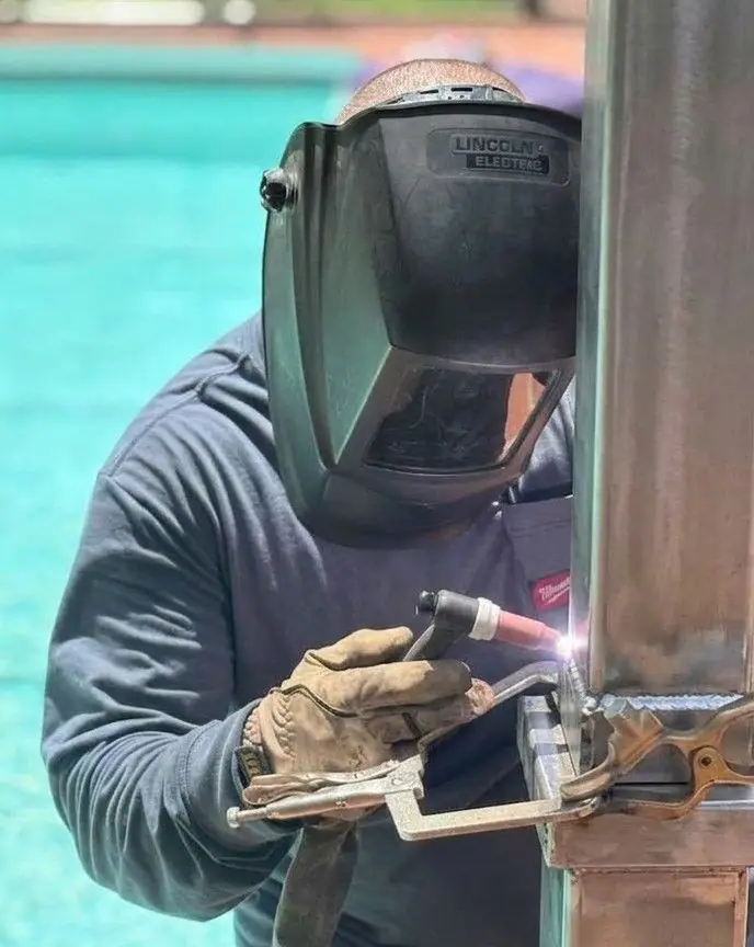 TIG welding a square metal post beside a pool