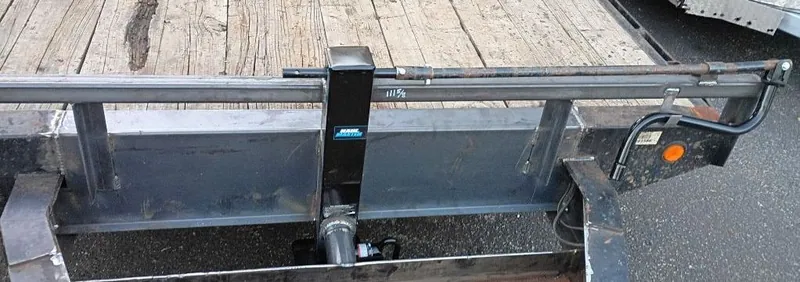 Trailer jack mounted at the front rail of a wood-deck flatbed trailer