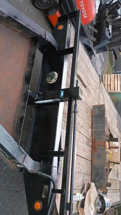 Top-down view of a trailer jack mount welded to the side rail of a flatbed trailer