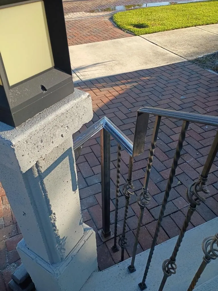 Black step railing with twisted balusters beside a brick paver walkway